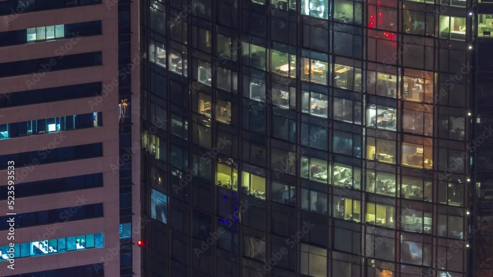 Windows in high-rise building glass exterior in the late evening with glowing and blinking interior lights on timelapse. Aerial top view Windows in high-rise building glass exterior in the late evening with glowing and blinking interior lights on timelapse. Aerial top view