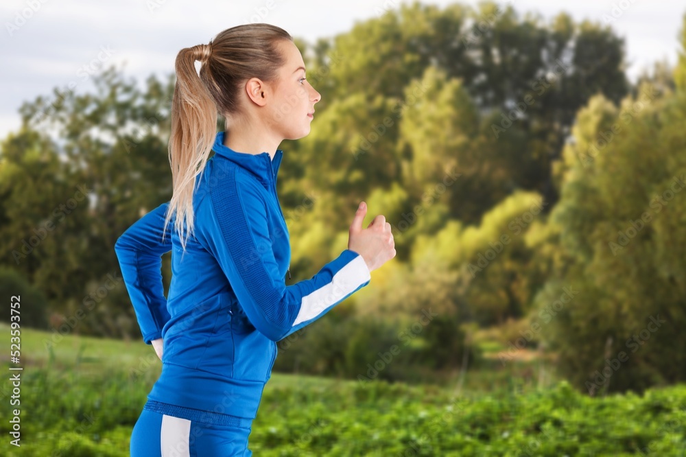 Smiling young woman in sportswear jogging at park on sunny day. Smiling young woman in sportswear jogging at park on sunny day.