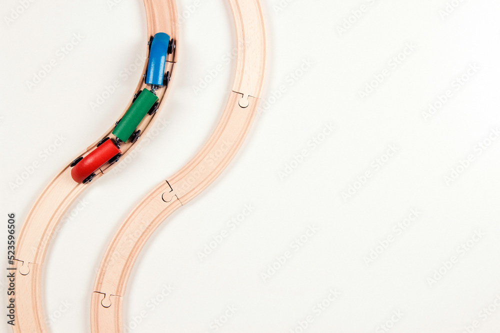 Children toys background. Wooden toy train on curve wooden railways on white background. Top view, copy space Children toys background. Wooden toy train on curve wooden railways on white background. Top view, copy space