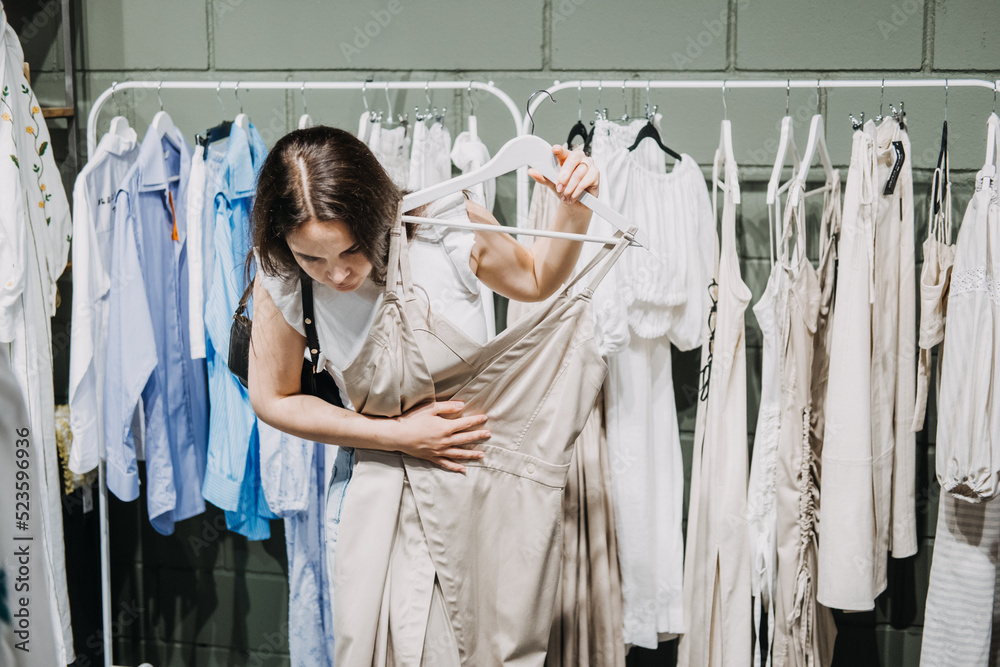 Fototapeta premium Sustainable fashion, slow fashion, Conscious shopping. Young Latina woman shopping in modern clothing store.