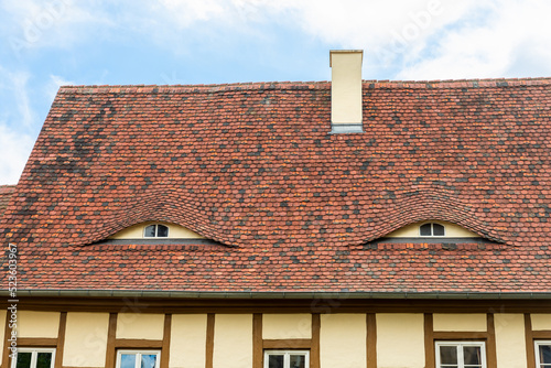 Old beautiful european german fachwerk building rooftop with eye shaped windows and chimney. Typical traditional ancoent house roof architecture in Europe. Funny face-shaped pareidolia facade photo