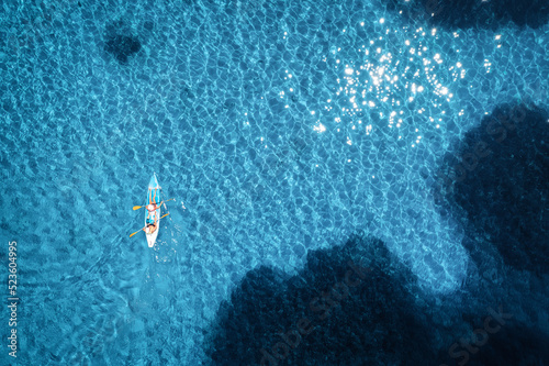 Aerial view of kayak with people in blue sea at sunset in summer. Floating canoe in transparent azure water. Sardinia island, Italy. Tropical landscape. Sup board. Active travel. Top view. Sport