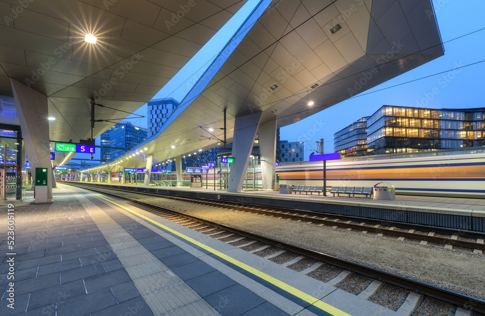 High speed train in motion on the railway station at night. Moving red