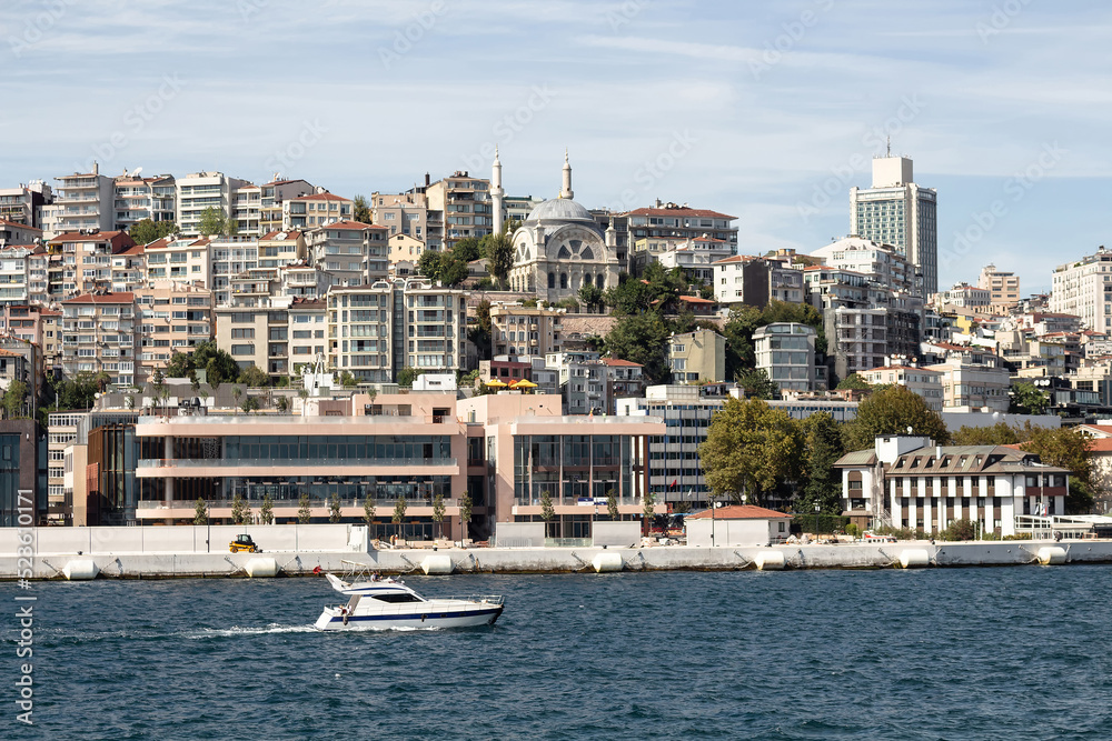 View of a yacht on Bosphorus and Gunussuyu area of Beyoglu district in Istanbul. It is a sunny summer day.