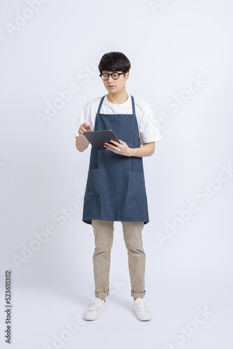 Full body portrait of Asian male Barista taking drink menu order or cashless payment with tablet isolated white background