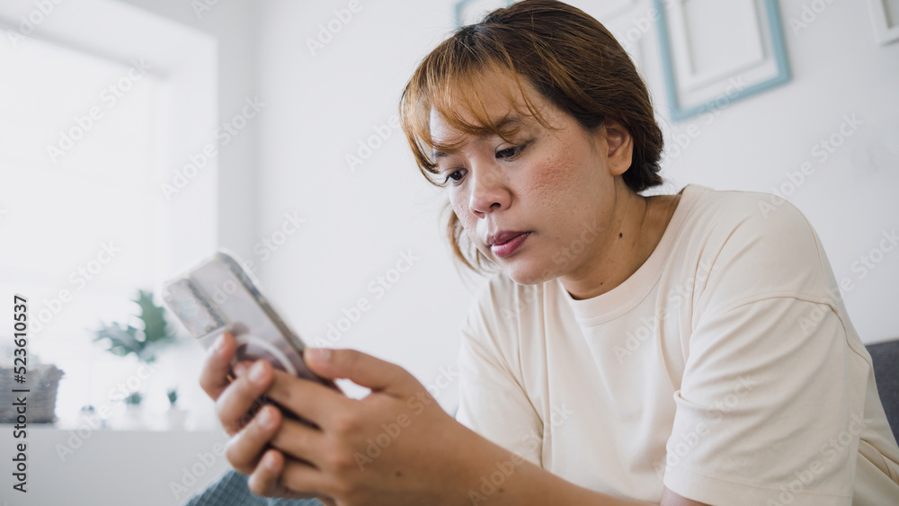 Smartphone content viewing concept , Asian woman holding and looking at smartphone screen in the living room. Smartphone content viewing concept , Asian woman holding and looking at smartphone screen in the living room.
