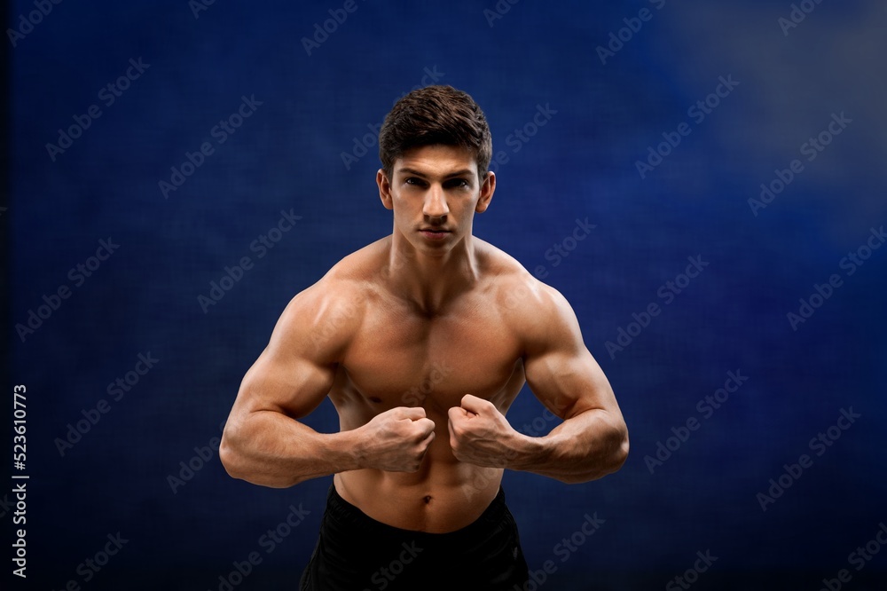 Brutal sweaty strong young man athlete with naked body standing showing strong pumped up biceps. Sport men body concept.