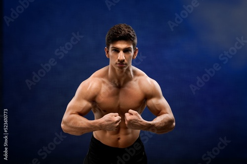Brutal sweaty strong young man athlete with naked body standing showing strong pumped up biceps. Sport men body concept. © BillionPhotos.com