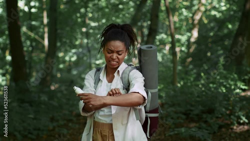 Young irritated african american woman tourist scratching hand after mosquito bite wiht repellent in forest, free space