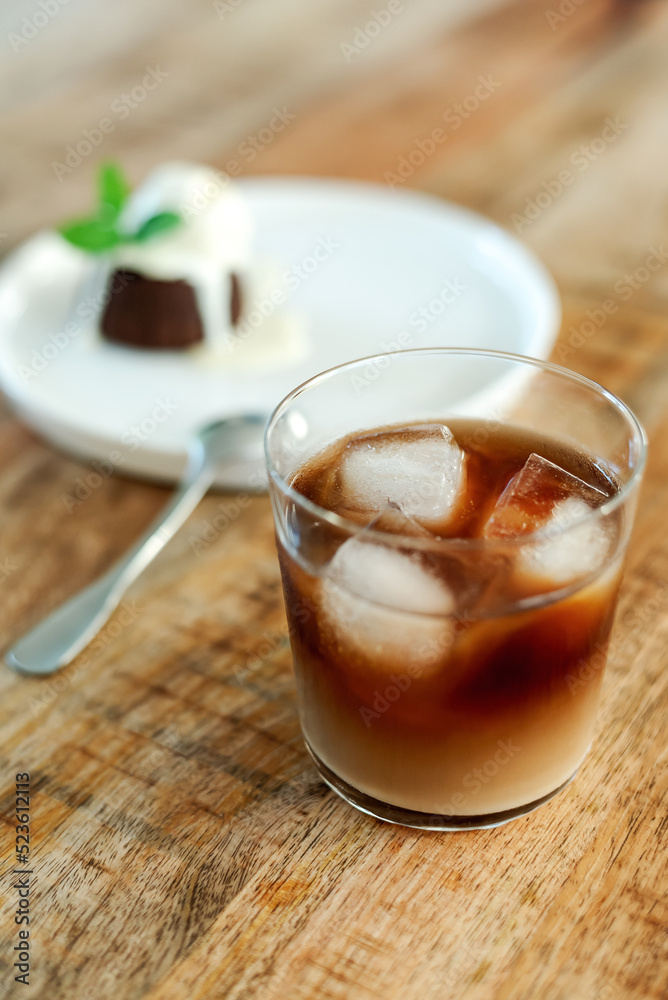 Overhead view of iced coffee in a glass on a wooden table. Overhead view of iced coffee in a glass on a wooden table.