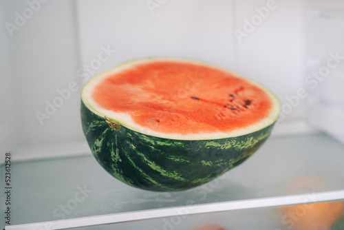 Half of fresh sliced watermelon on a shelf in the refrigerator. Authentic lifestyle. Home cooking, preparation of organic food