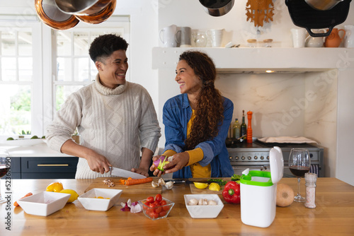 Image of happy diverse couple preparing meal in kitchen