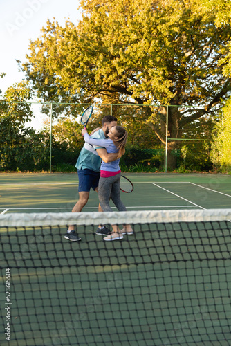 Happy caucasian couple playing tennis embracing on outdoor tennis court © WavebreakMediaMicro