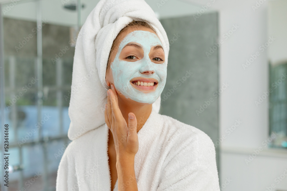 Φωτογραφία Portrait of happy caucasian woman wearing robe, applying beauty face mask in bat