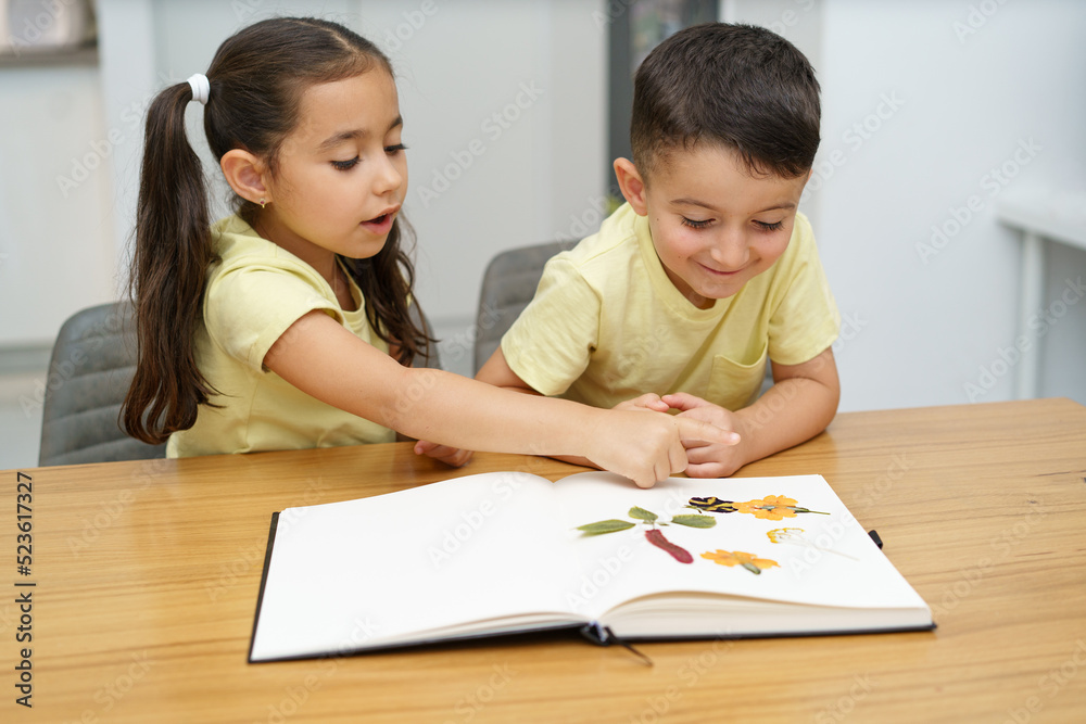 Children making herbarium. Funny kids arranging pressed flowers in a book. Children making herbarium. Funny kids arranging pressed flowers in a book.