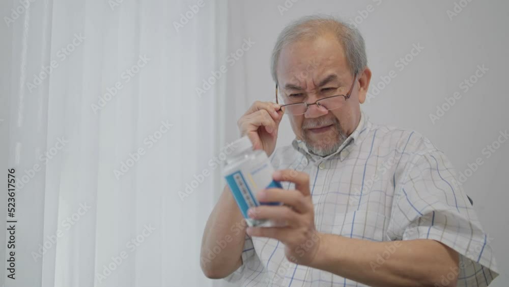 Asian senior man with farsighted reading prescription on medicine bottle at nursing home. Medical insurance and health care concept Asian senior man with farsighted reading prescription on medicine bottle at nursing home. Medical insurance and health care concept