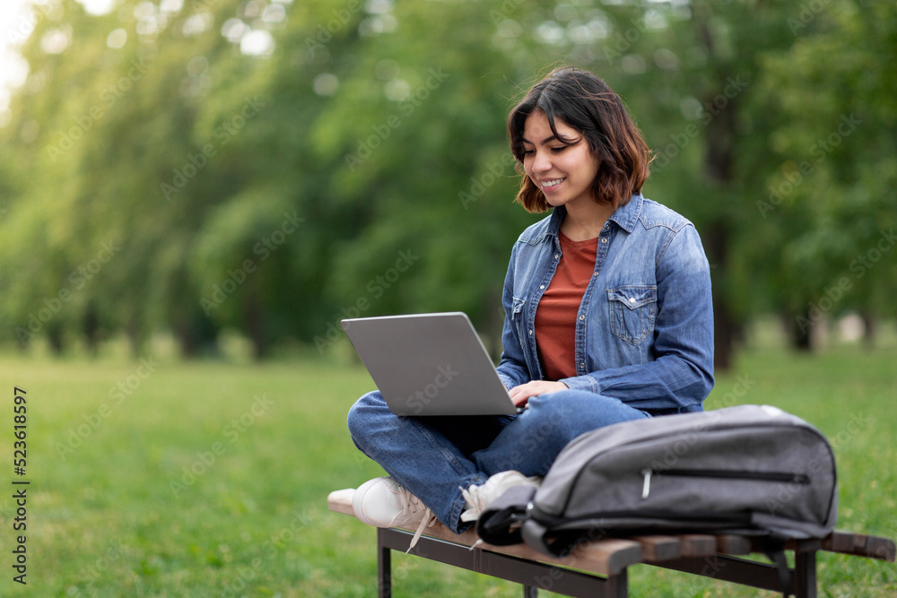 Distant Learning. Arab Female Student Using Laptop While Sitting On Bench Outdoors Distant Learning. Arab Female Student Using Laptop While Sitting On Bench Outdoors