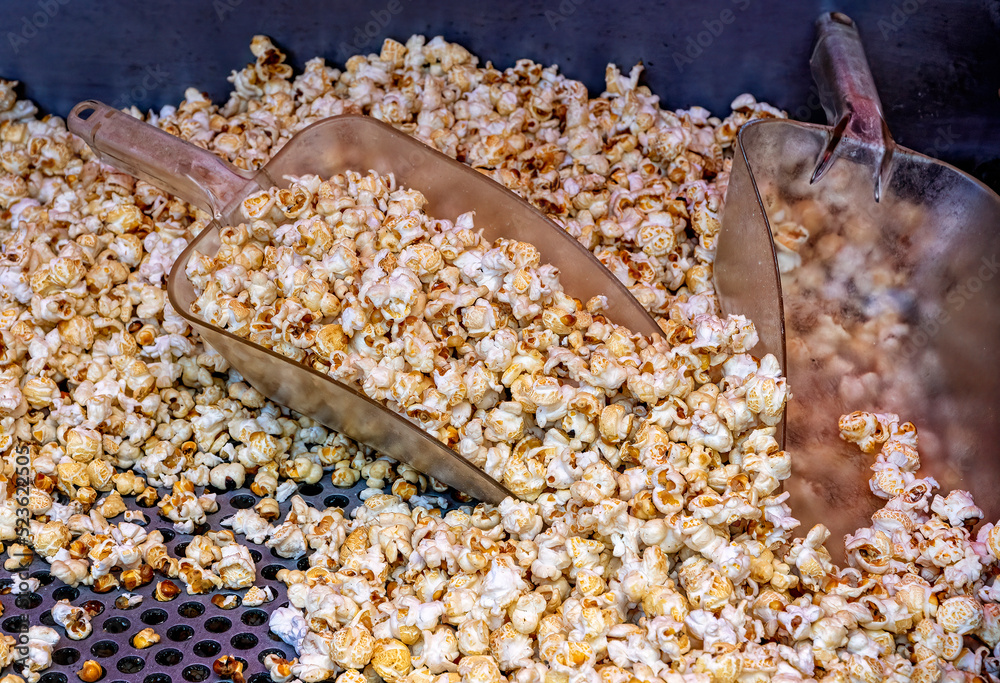 Salting and mixing freshly popped kettle corn. Operator mixes it with