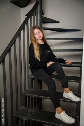 beautiful blonde young girl with long hair in black dress sitting on the stairs © Tetatet