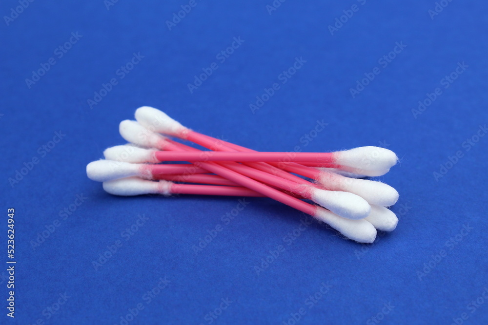 A bunch of cotton buds lie on a blue background. A bunch of cotton buds lie on a blue background.