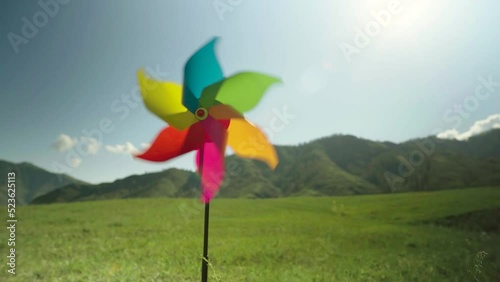 Pinwheel close-up is spinning by force of wind in background of green mountains