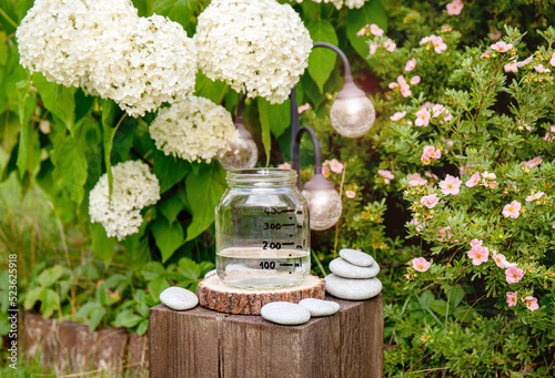 Handmade rain water gauge made of glass jar, measuring rain in home garden. Raining outdoors in garden. Also known as udometer, pluvia metior, pluviometer, ombrometer and hyetometer.