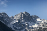 stunning high grey mountain with snow fields on a sunny day and blue sky, alpine area	