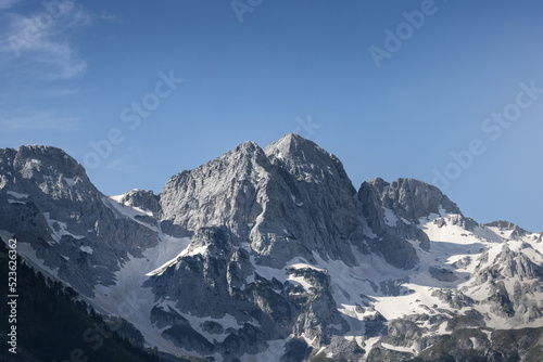 stunning high grey mountain with snow fields on a sunny day and blue sky, alpine area 