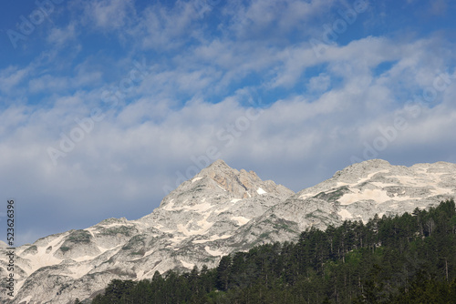 stunning high grey mountain with snow fields on a sunny day and blue sky, alpine area