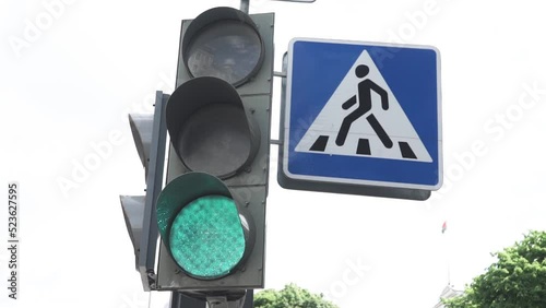 traffic light signal in the city, works green and switches to red. Road sign pedestrian crossing, old houses in the background