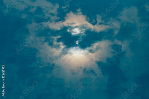 reflection of the bright sun, clouds and blue sky on the surface of the water