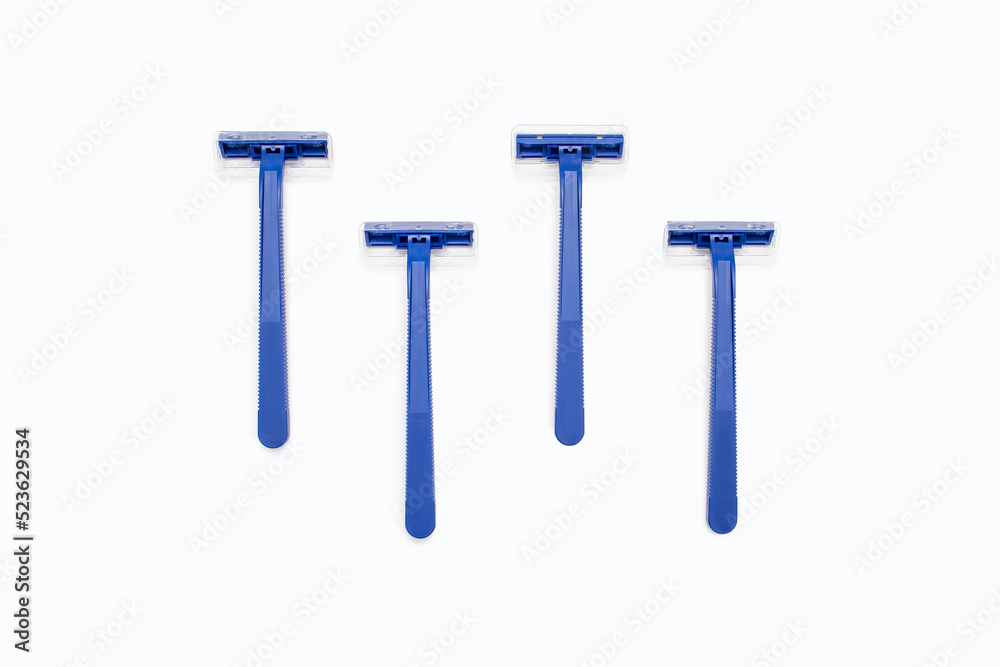 Four blue plastic razors on a white background. Disposable blue plastic razors lie on a white background. Shaving and care product for smooth skin. Razor without replaceable blades Four blue plastic razors on a white background. Disposable blue plastic razors lie on a white background. Shaving and care product for smooth skin. Razor without replaceable blades