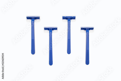 Four blue plastic razors on a white background. Disposable blue plastic razors lie on a white background. Shaving and care product for smooth skin. Razor without replaceable blades