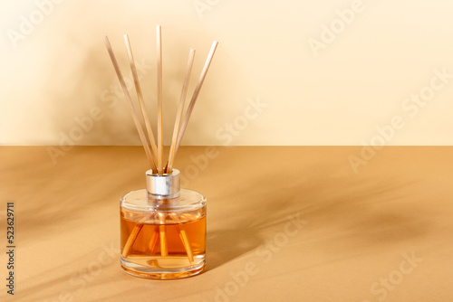 reed diffuser bottle on a beige background. Incense sticks for the home with a floral scent. The concept of eco-friendly fragrance for the home