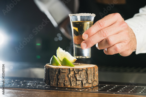 Tequila. a man holds a glass of tequila shot, the trend drinks concept.
