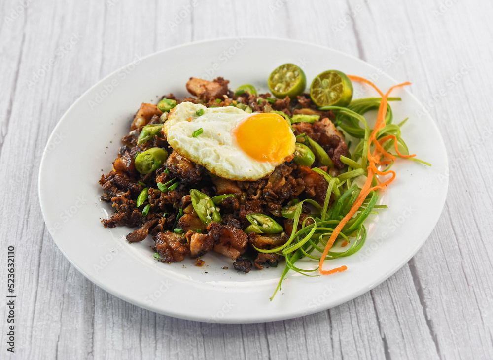 Pork Bagnet Sisig with egg served in dish isolated on grey wooden background side view of fastfood Pork Bagnet Sisig with egg served in dish isolated on grey wooden background side view of fastfood
