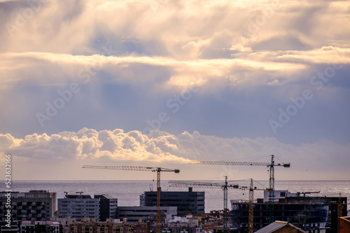 Skyline of the city of Barcelona (Spain) with various cranes of new constructions and the sea in the background.