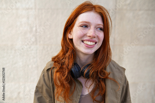 Konstfotografi Happy teen stylish cool redhead fashion girl model standing on urban wall background laughing
