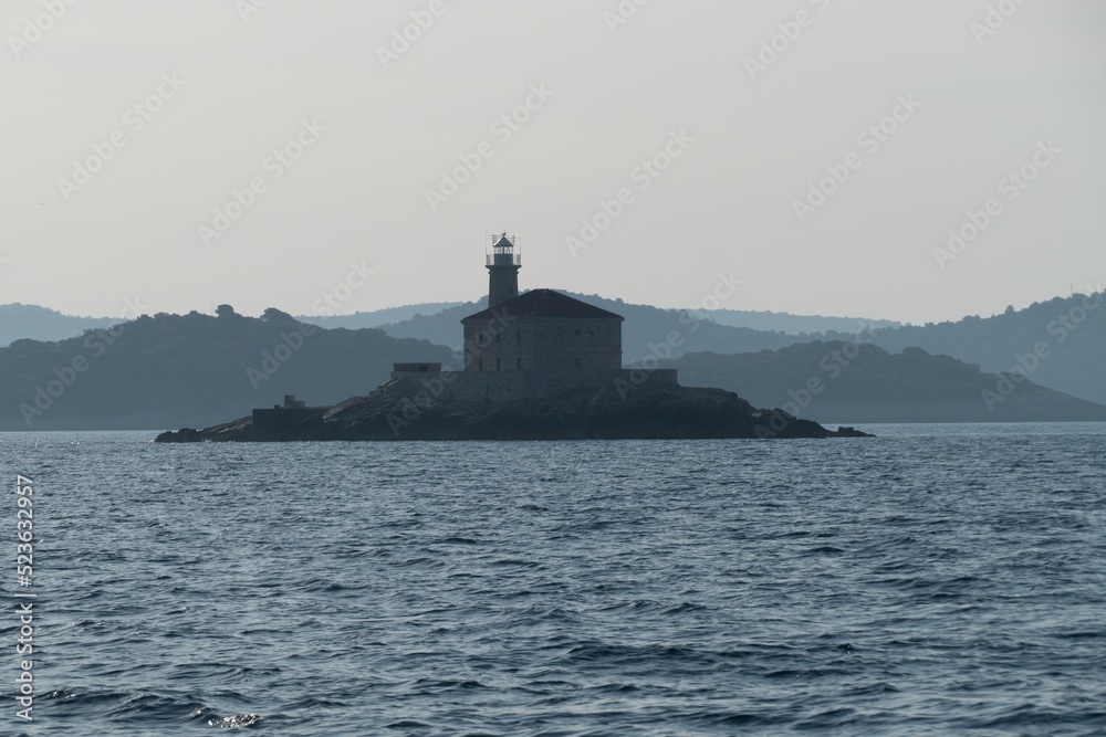 lighthouse at a small rocky island in sea
