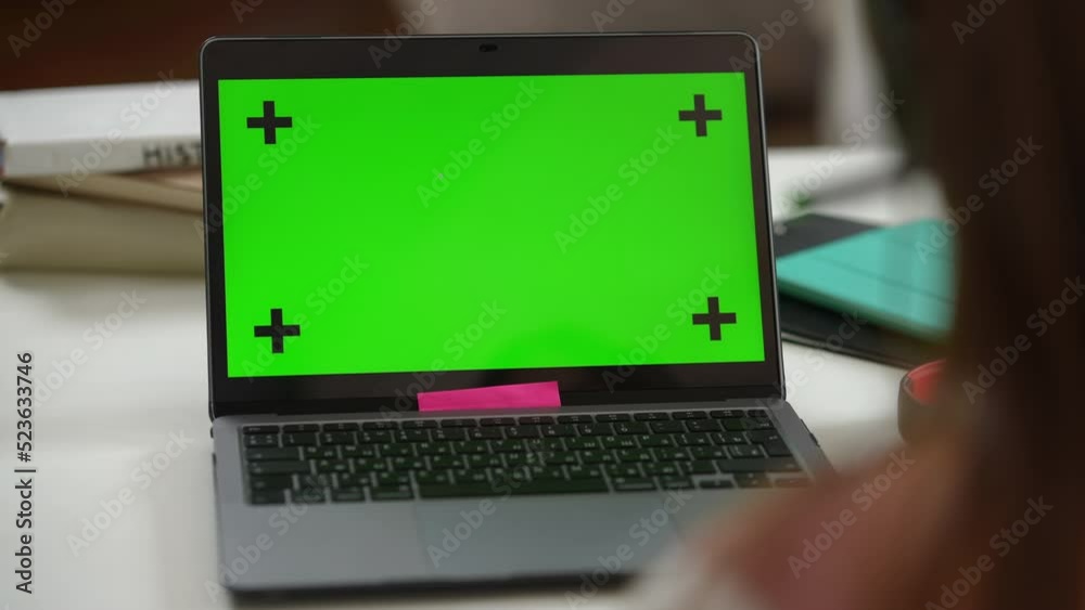 Close-up green screen laptop with video chat and unrecognizable schoolgirl in headphones chatting studying online. Teenage Caucasian girl with chromakey device indoors. Convenience and education Close-up green screen laptop with video chat and unrecognizable schoolgirl in headphones chatting studying online. Teenage Caucasian girl with chromakey device indoors. Convenience and education
