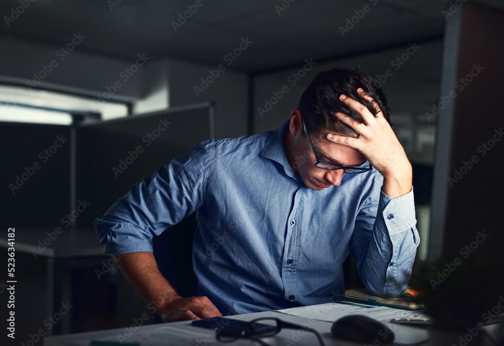 Obraz premium Stressed, tired business man suffering from headache, working late night in the office. Worried male entrepreneur thinking about problems and project deadline feeling burnout, distress and exhausted.