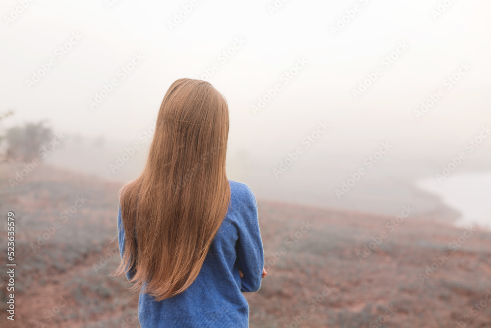 girl walking on a foggy morning, back view