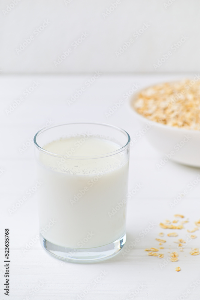bowl of granola with a spoon and a glass of oat milk. white wooden background. top view. copy space.