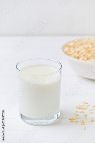 bowl of granola with a spoon and a glass of oat milk. white wooden background. top view. copy space.