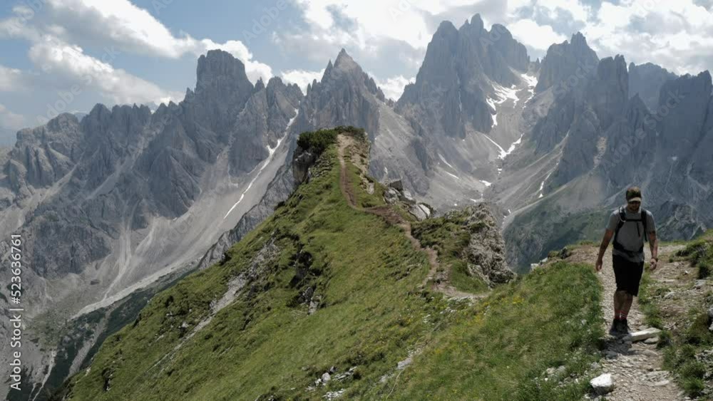 Man hiking from the mountain top overlooking Cadini group mountains Man hiking from the mountain top overlooking Cadini group mountains