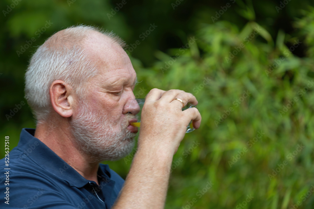 Obraz premium old man is drinking softdrink in the garden