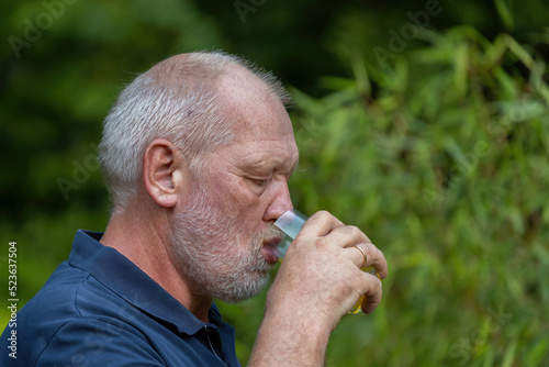 old man is drinking softdrink in the garden