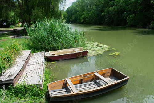 River creek  and wooden boats on a small pier  in the water, river cane and water lily leaves behind and under boats