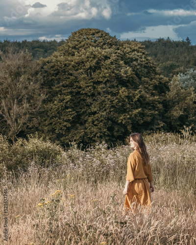woman in yellow dress walking through long grass © Rachel
