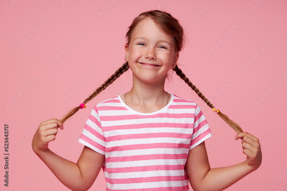 Portrait of surprised cute toddler girl child standing isolated over pink background. holding hands on two pigtails. Looking at camera. Portrait of surprised cute toddler girl child standing isolated over pink background. holding hands on two pigtails. Looking at camera.